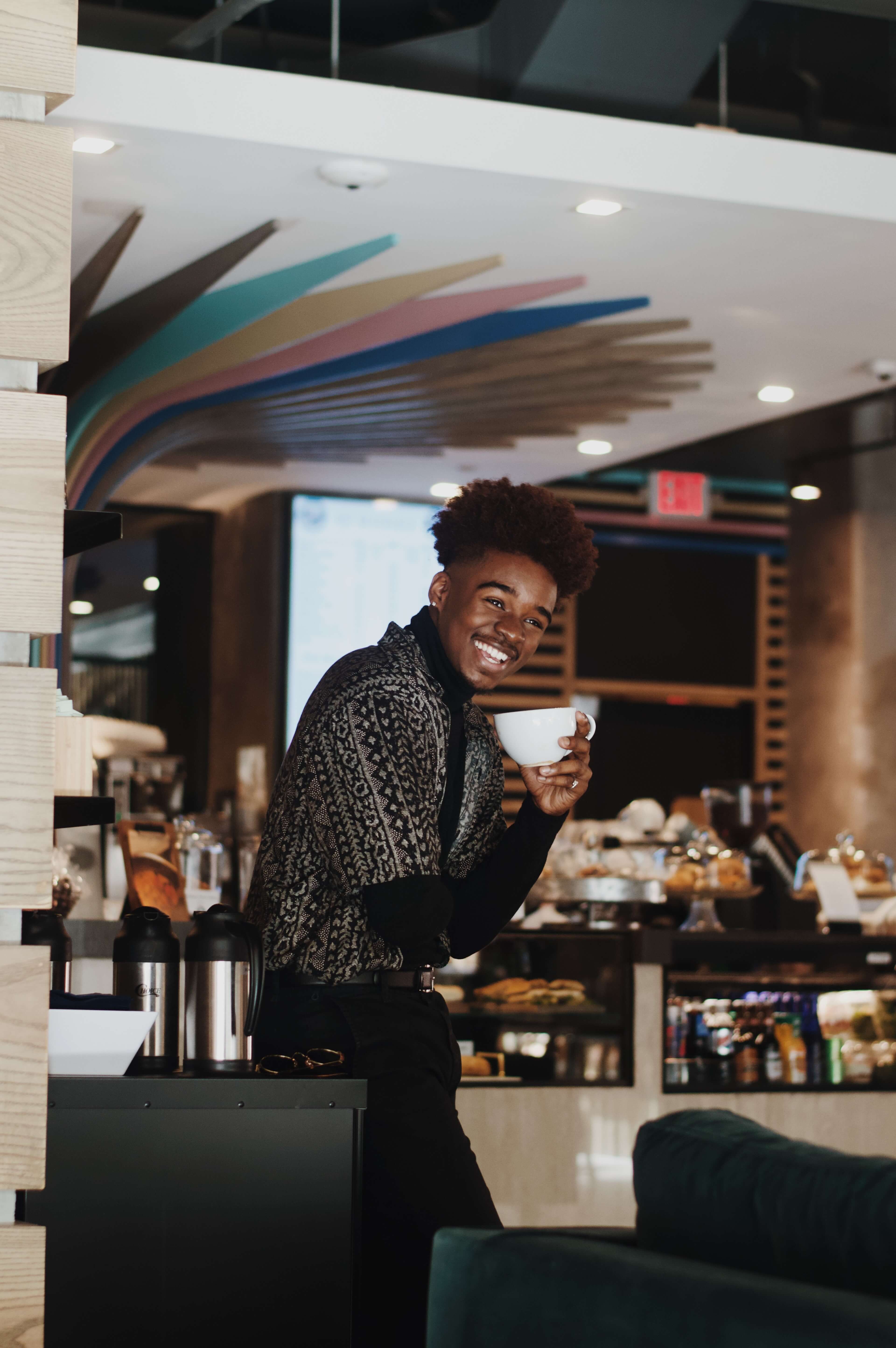 Jongen lachend koffie drinken in koffiebar